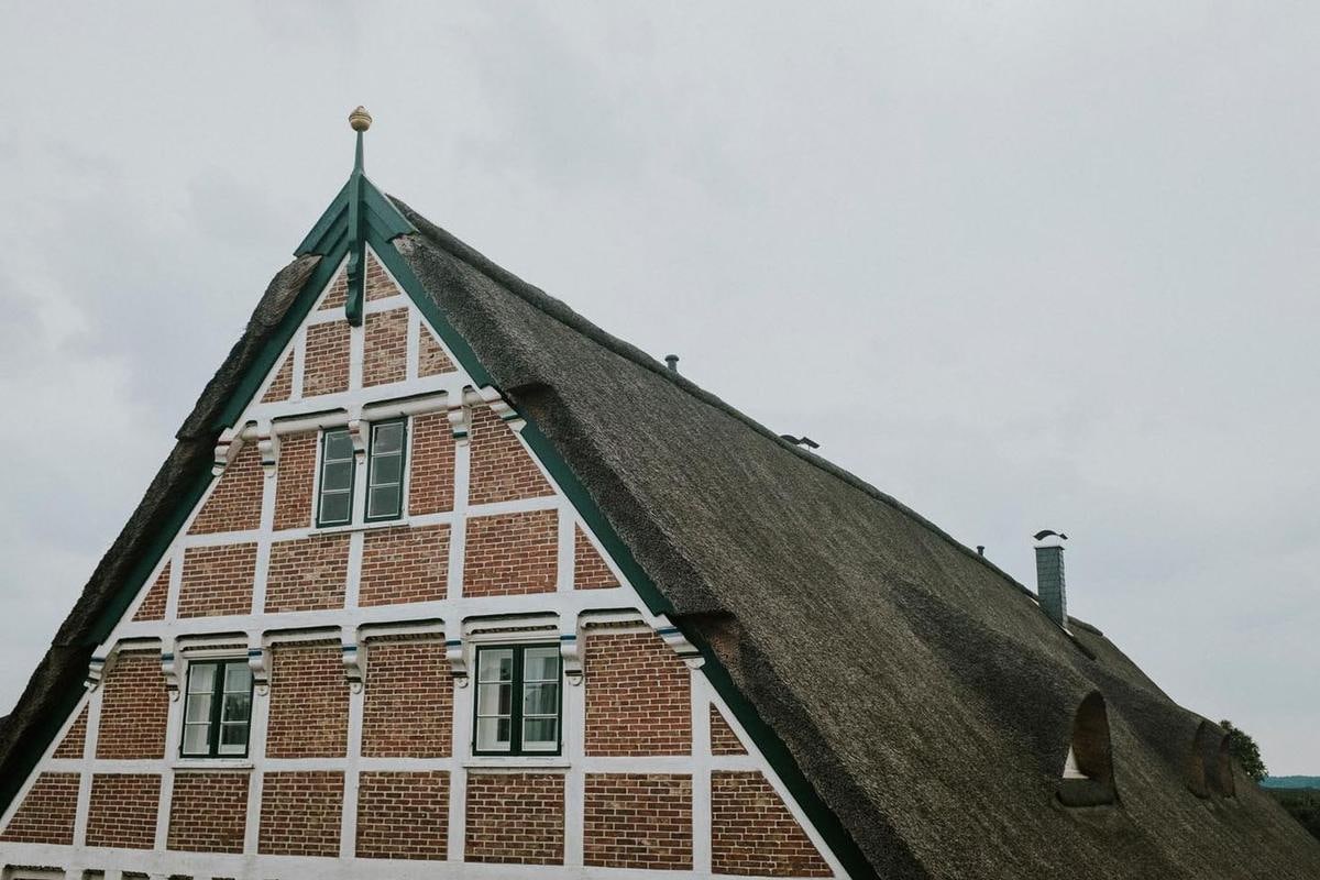 Hoher Fachwerkgiebel, das Reetdach reicht weit nach unten.