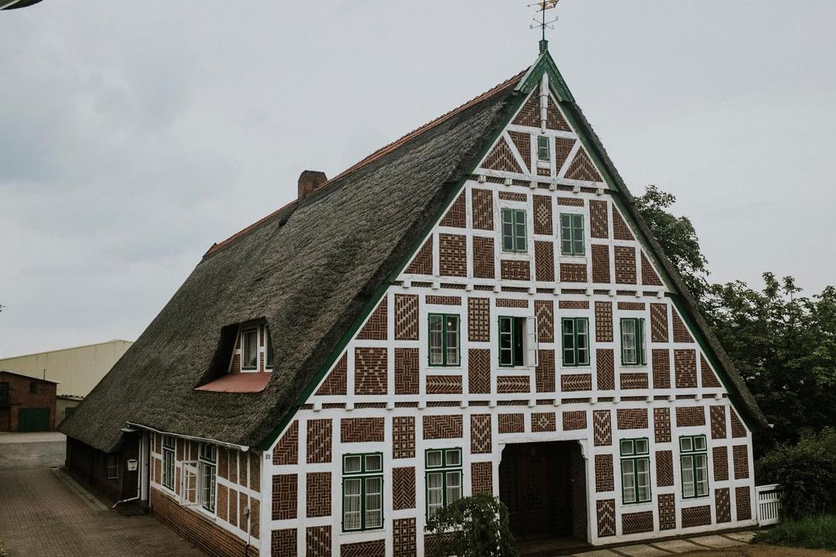 Fachwerkgiebel mit Backsteinmustern und Reetdach.