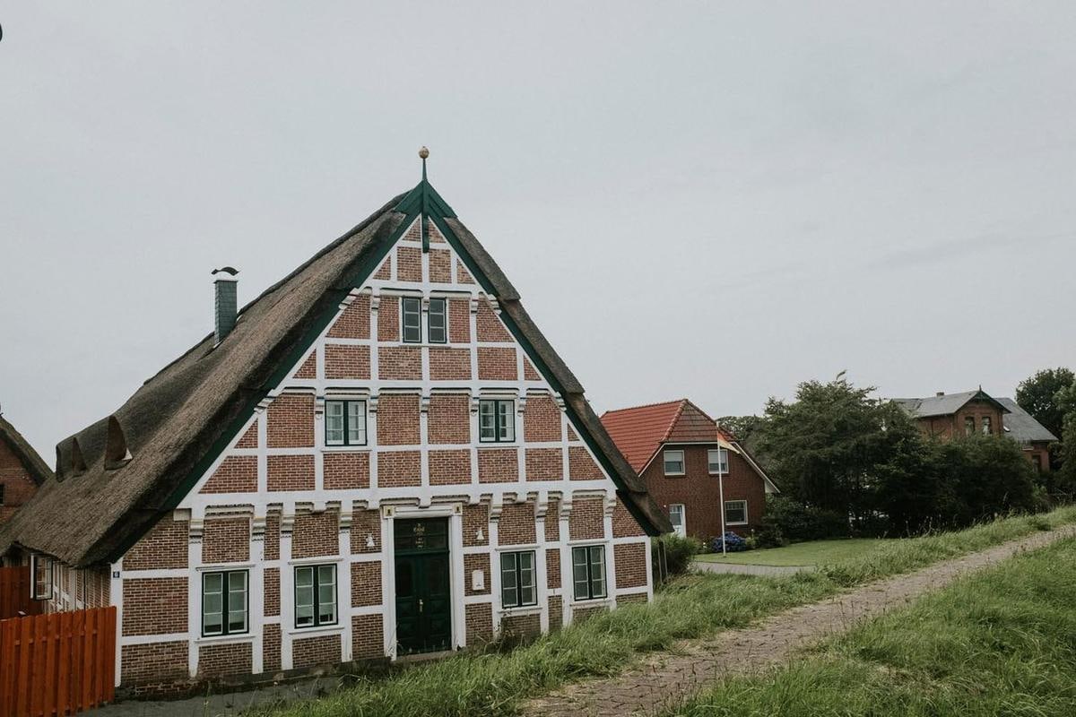 Fachwerkgiebel mit Reetdach an einem Weg.