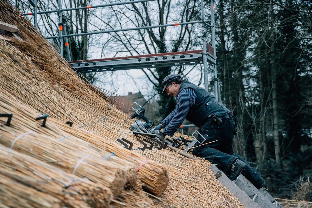 Ein Handwerker liegt auf dem Dach und arbeitet an der Bindung.