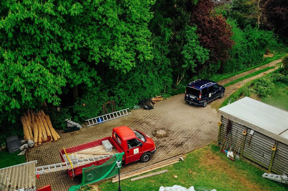Blick von oben auf einen Hof mit rotem Pick-up und Reet.