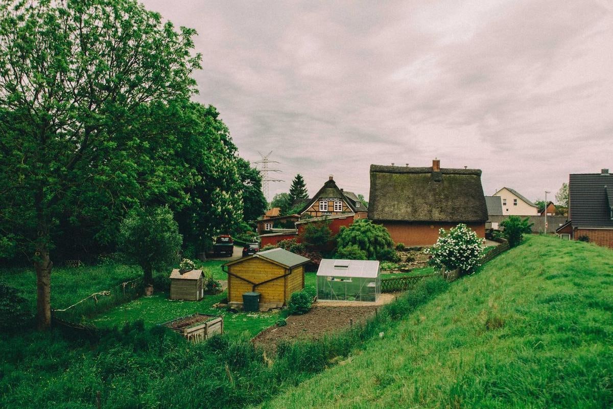 Reetdachhaus mit Garten, vorne eine Böschung mit Gras.