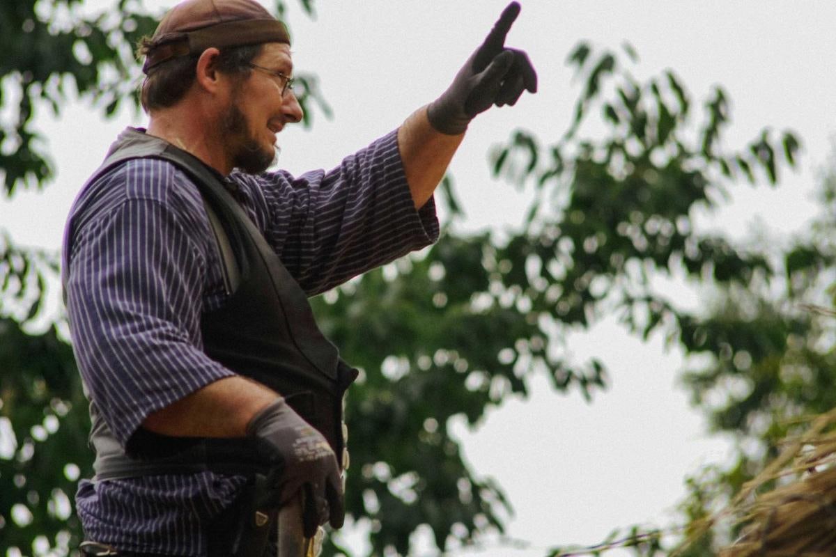 Handwerker zeigt mit ausgestrecktem Arm nach oben.