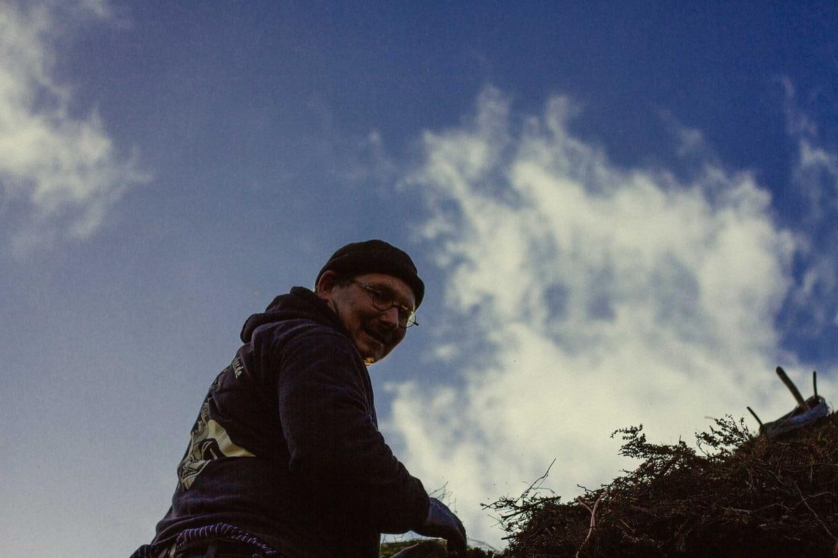 Silhouette eines Handwerkers am Dach vor Wolken.