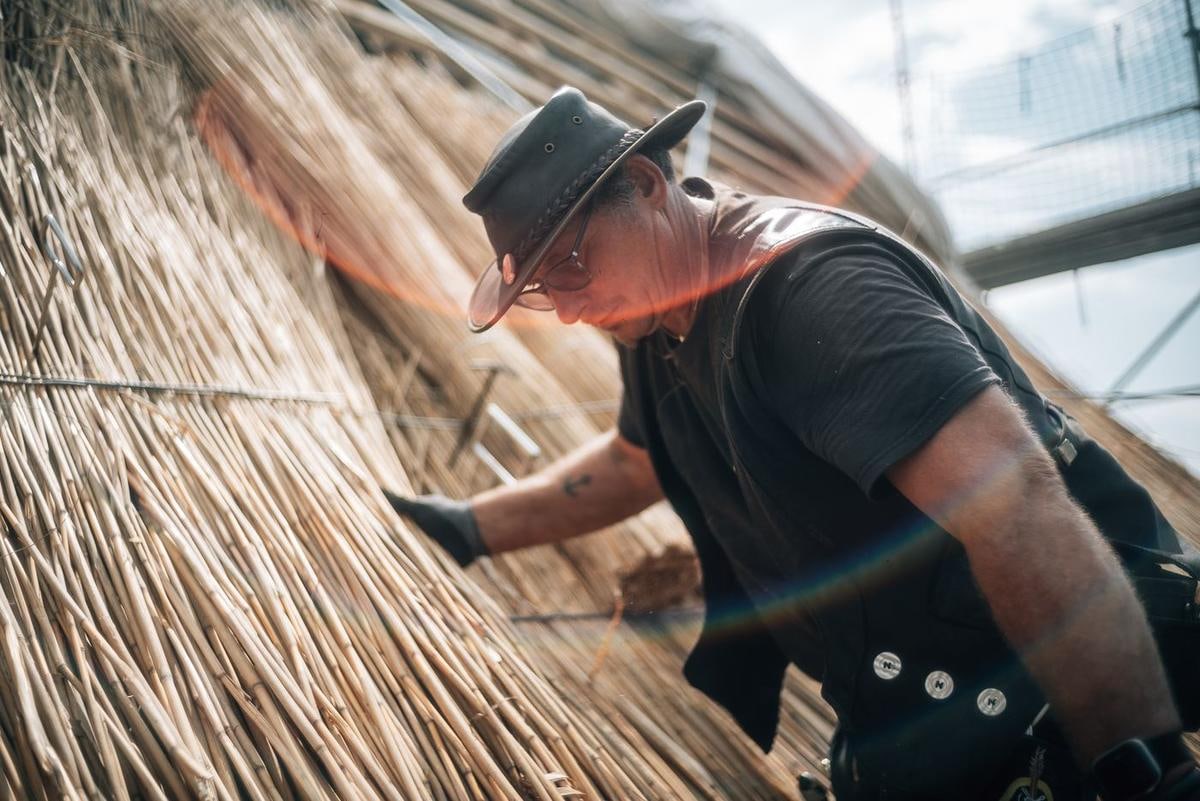 Handwerker am Reet, im Bild Lichtreflexe.