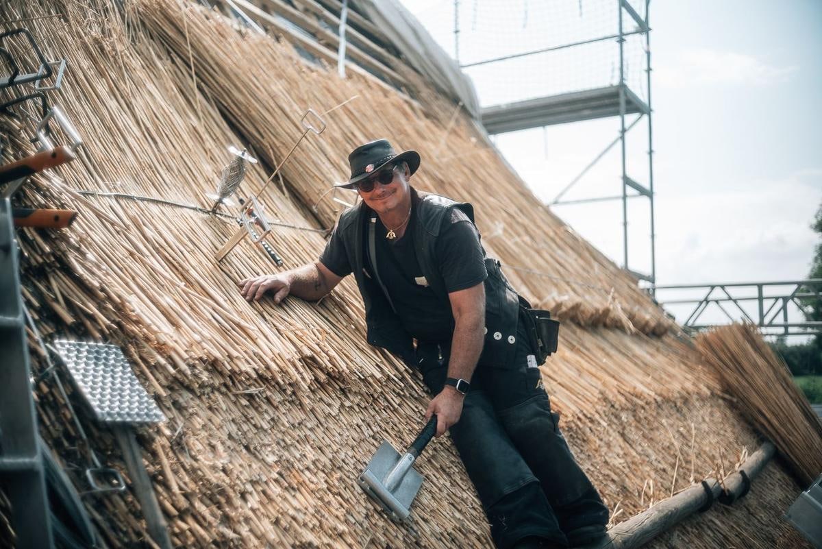 Handwerker arbeitet an der Fläche, rechts das Gerüst.