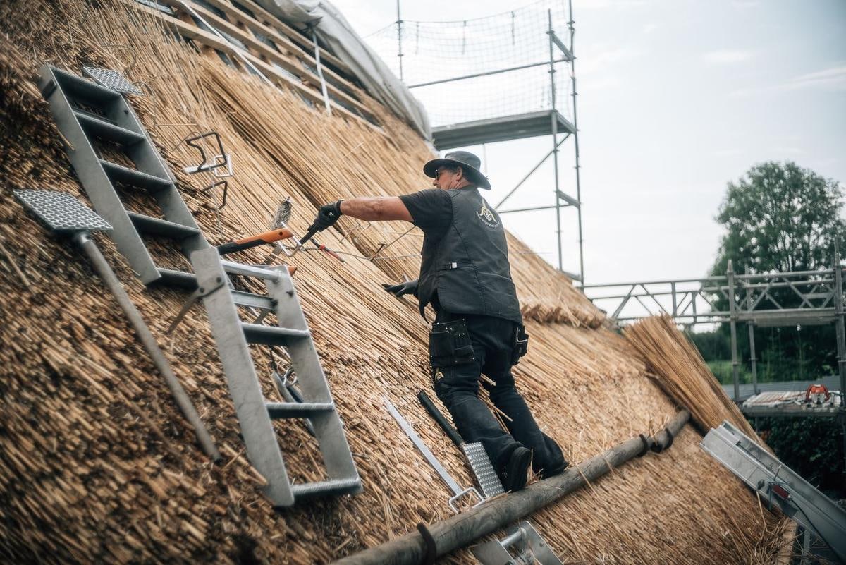 Handwerker auf dem Dach neben einer Leiter.