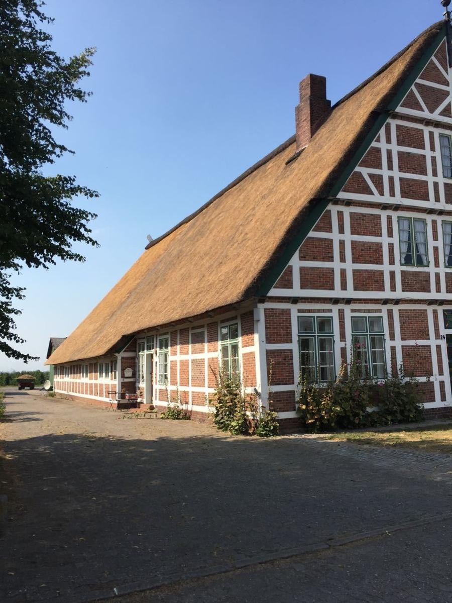 Reetdach mit Walm an der Giebelecke, Fachwerk darunter.