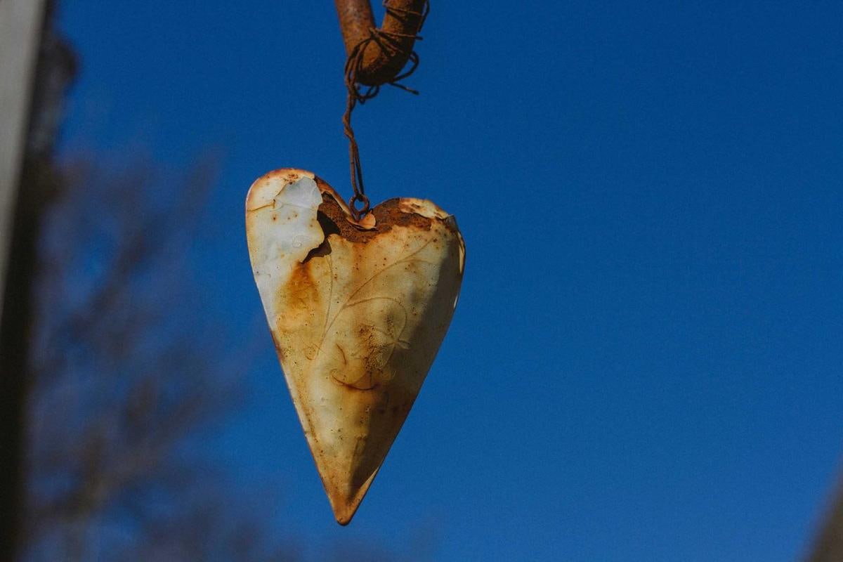 Herz aus Kupferblech hängt vor blauem Himmel.