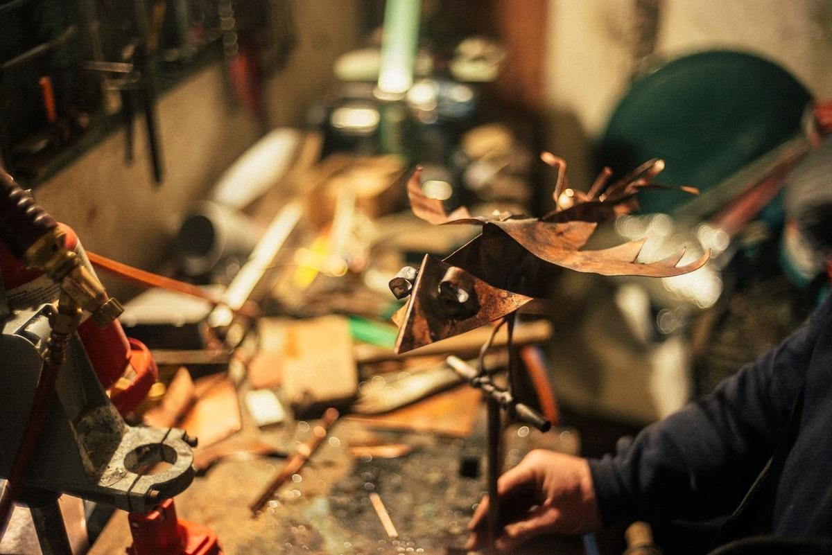 Werkstatt mit Werkzeugen, im Vordergrund ein Vogel aus Kupferblech.