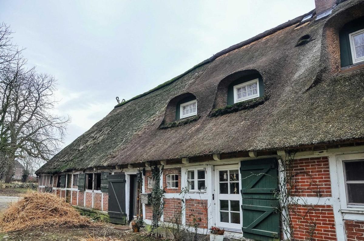 Langes Fachwerkhaus mit mehreren Gauben im alten Reetdach.