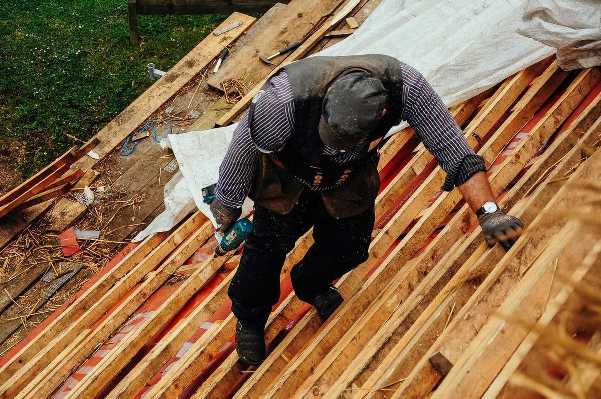Ein Handwerker steht auf frischer Holzlattung.