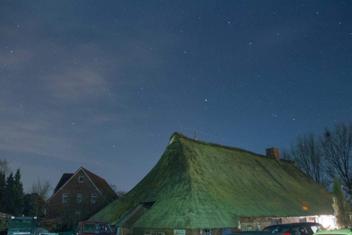 Grünes, moosiges Reetdach unter dem Nachthimmel.