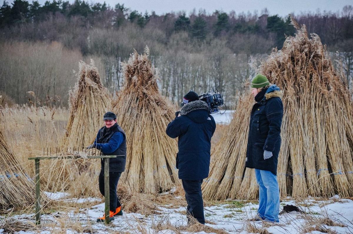 Mehrere Menschen zwischen hohen Reethocken auf Schnee.