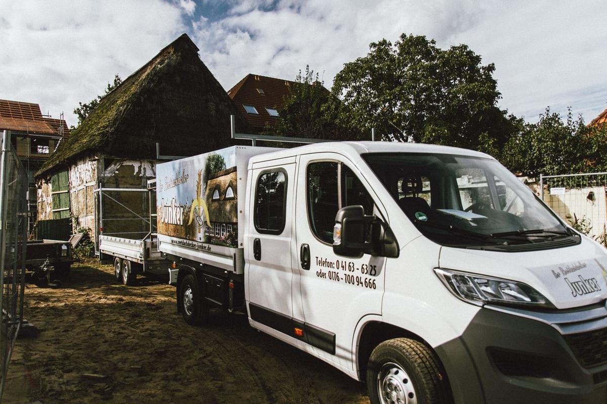 Weißer Transporter mit Pritsche vor der eingerüsteten Scheune.