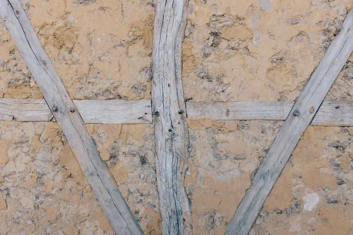 Helle Lehmflächen zwischen schrägen und senkrechten Holzbalken.
